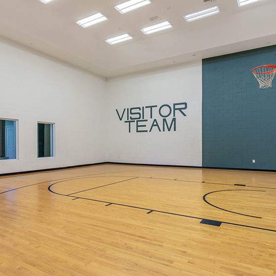 Gym with VISITOR TEAM written on the wall