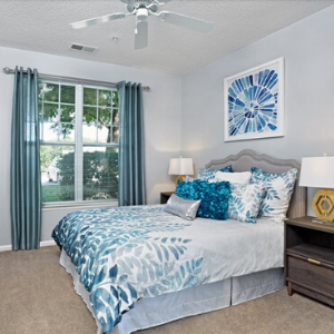Blexley at Heritage Bedroom with bed, blue curtains, and windows